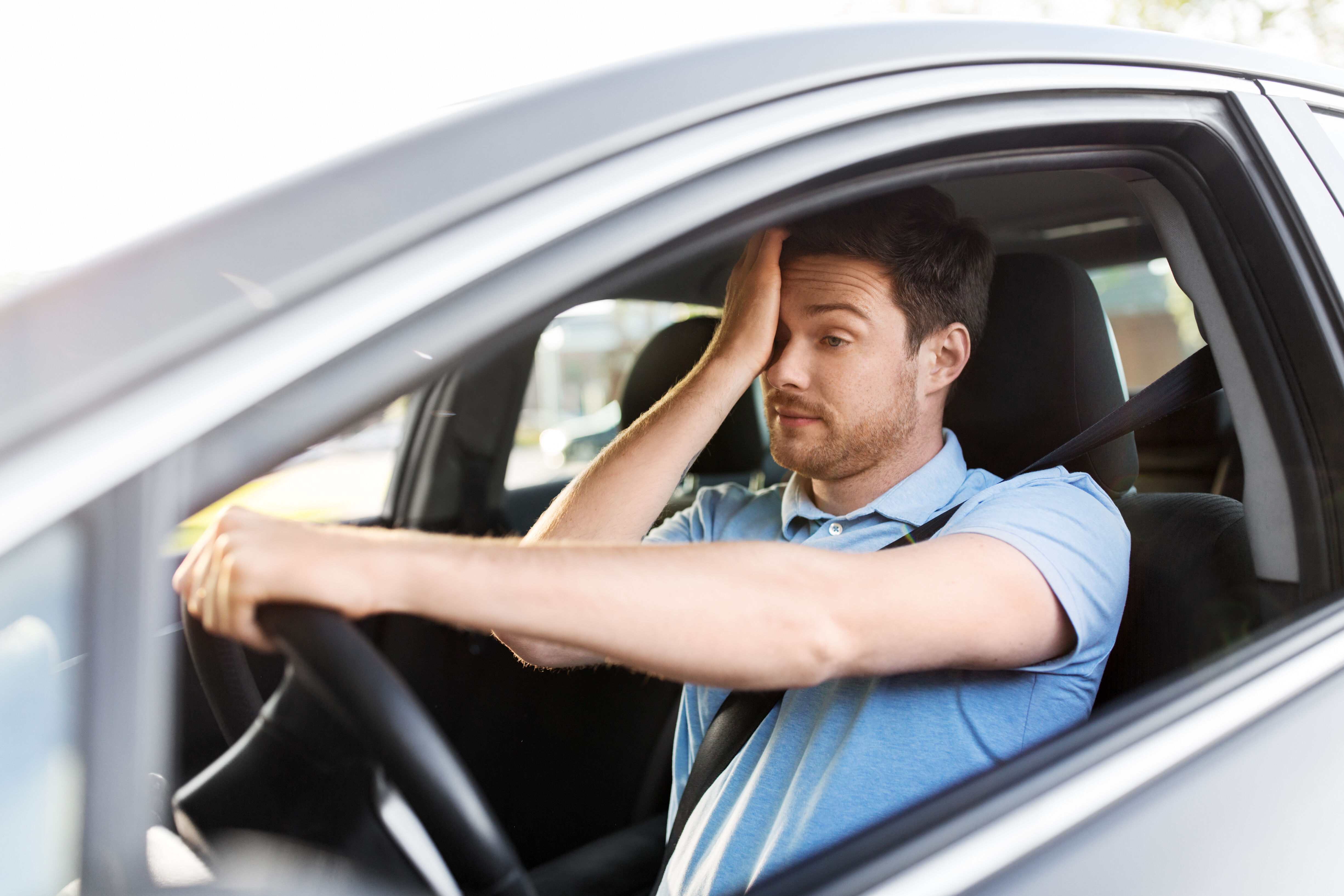 Man in car rubs his eyes